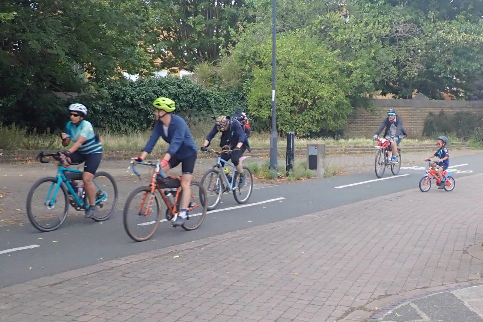 A blurry and out of focus shot o4 four adults and one child cycling on a marked cycleway.