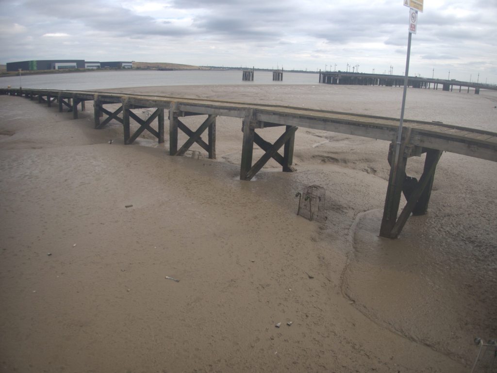 Muddy flatlands under a pier on the lower thames.