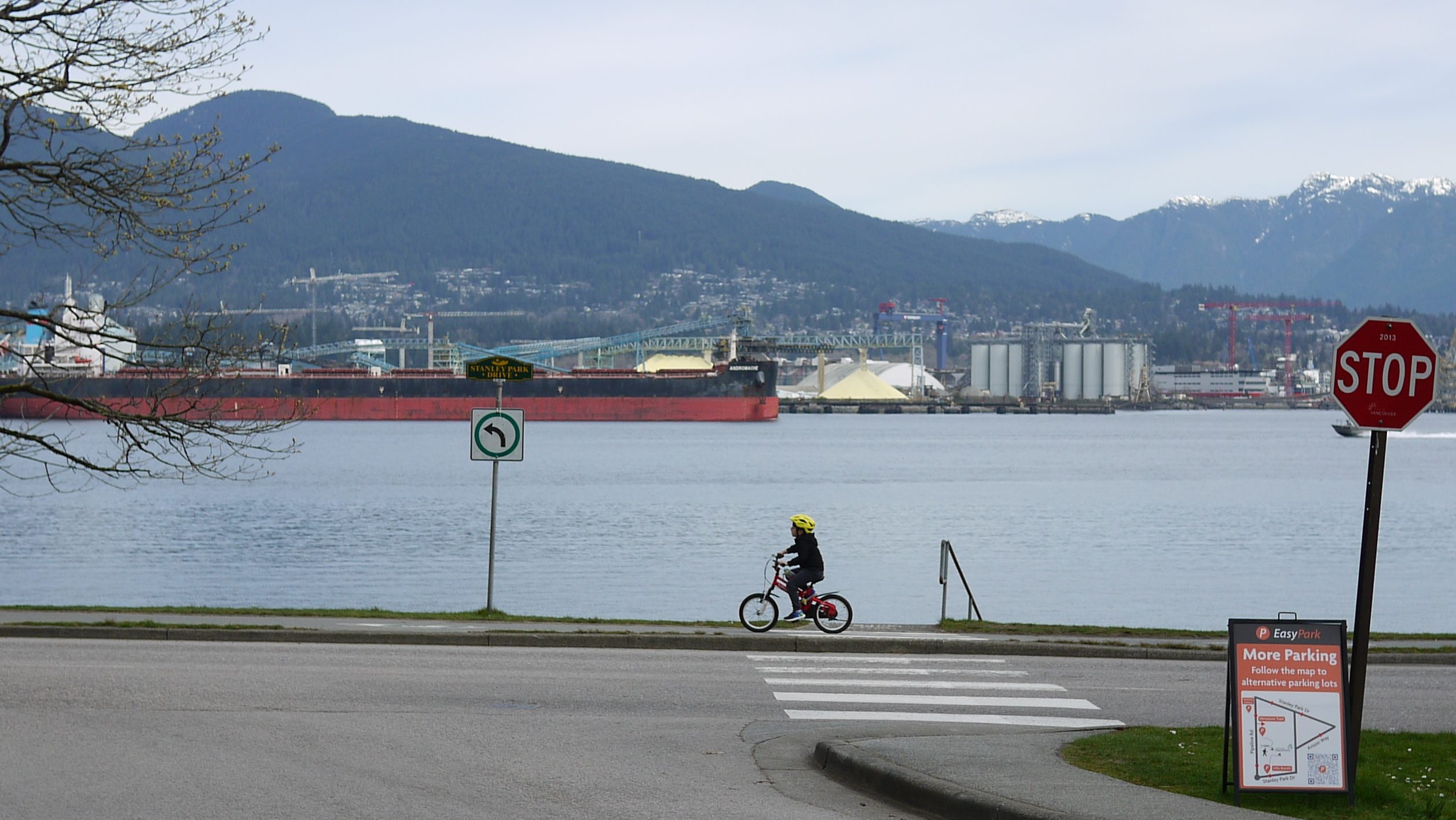 A child riding their bike along the Vancouver sea wall riding west.